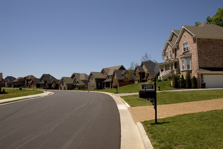 an empty road with grass on the side of a building
